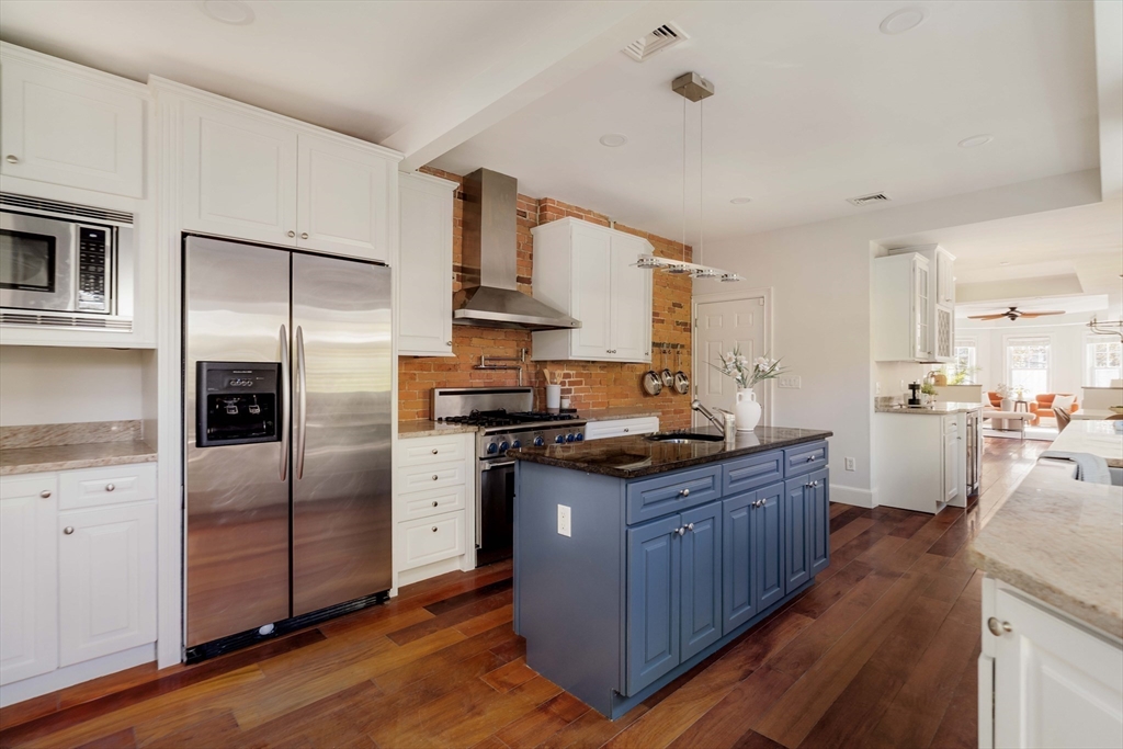 32 Hall Avenue, Unit 32 Somerville, MA 02144 - Photo 6 of 30 a kitchen with stainless steel appliances granite countertop a stove a refrigerator a sink a oven and wooden cabinets with wooden floor