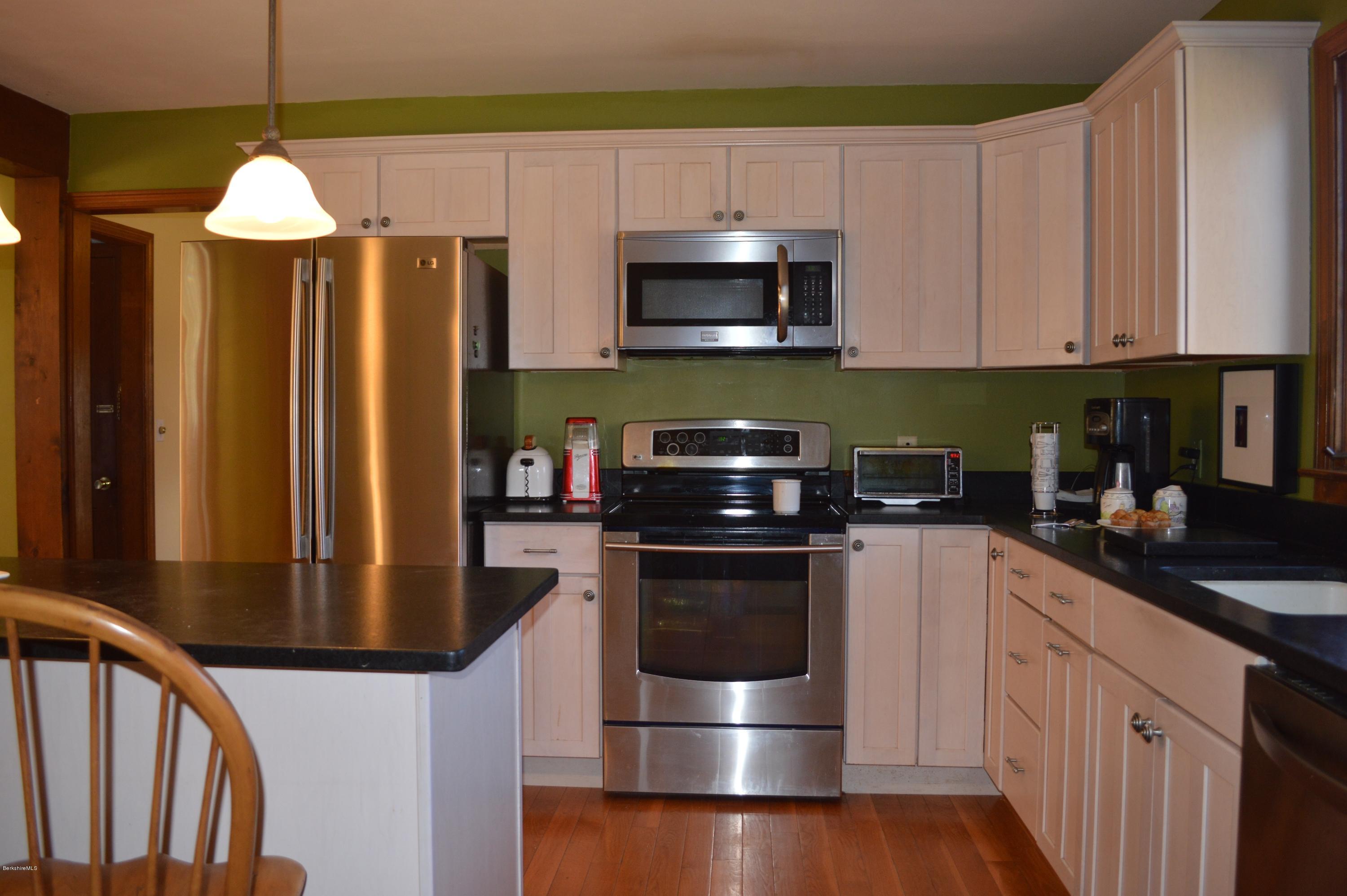 485 Devon Road Lee, MA 01238 - Photo 3 of 28 a kitchen with stainless steel appliances a stove a microwave a sink and cabinets