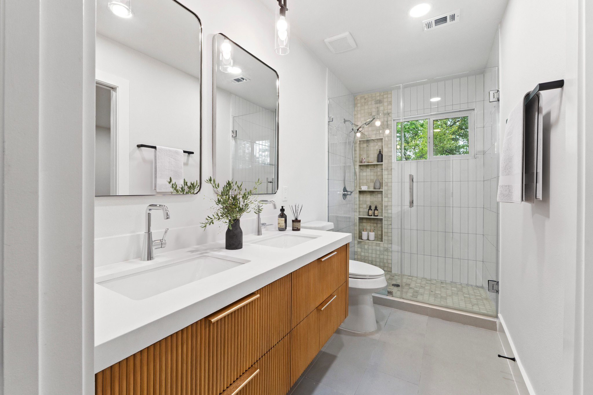 1608 Springer Lane Austin, TX 78758 - Photo 16 of 35 Double vanity with integrated sinks and a fluted wood-finish base, dual framed mirrors, and chrome fixtures