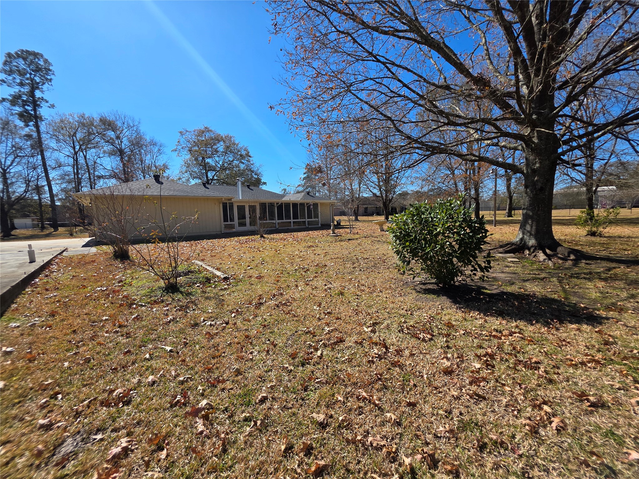 8708 West Fox Road Orange, TX 77632 - Photo 20 of 23 Spacious backyard with mature trees and a view of the house's rear side. The lawn is expansive, providing ample outdoor space for activities and landscaping opportunities.