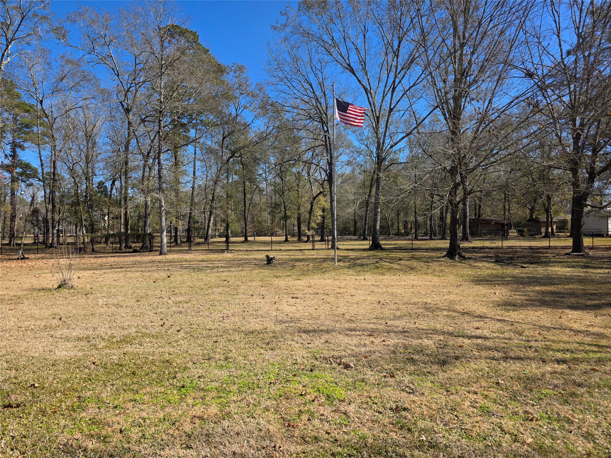 8708 West Fox Road Orange, TX 77632 - Photo 23 of 23 This spacious property features a large open yard with mature trees, offering plenty of natural beauty and privacy. An American flag adds a patriotic touch to the serene setting, ideal for outdoor activities or future landscaping projects.