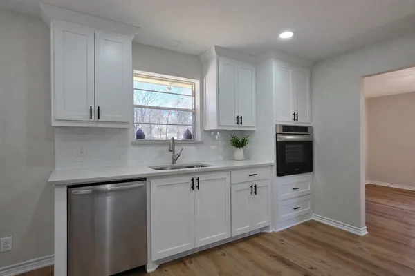 a kitchen with stainless steel appliances granite countertop a sink a stove and cabinets