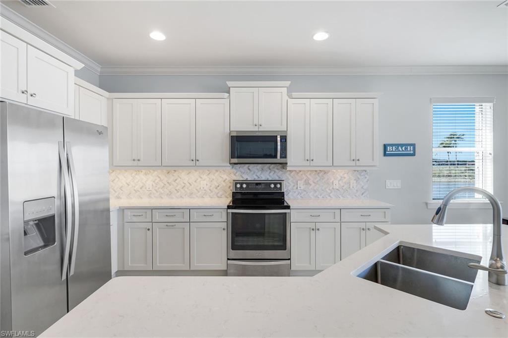 9060 Siesta Bay Drive, Unit 101 Naples, FL 34120 - Photo 11 of 49 a kitchen with white cabinets and stainless steel appliances