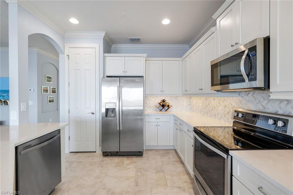 9060 Siesta Bay Drive, Unit 101 Naples, FL 34120 - Photo 9 of 49 a kitchen with stainless steel appliances granite countertop a refrigerator and a stove top oven