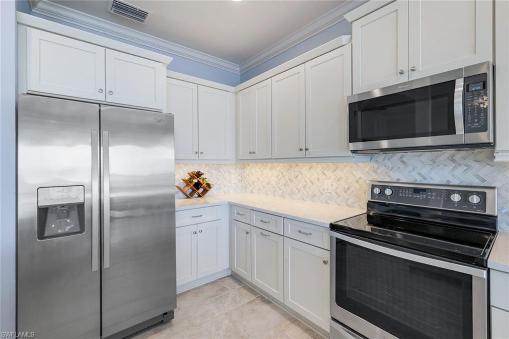 9060 Siesta Bay Drive, Unit 101 Naples, FL 34120 - Photo 10 of 49 a kitchen with stainless steel appliances white cabinets and a stove