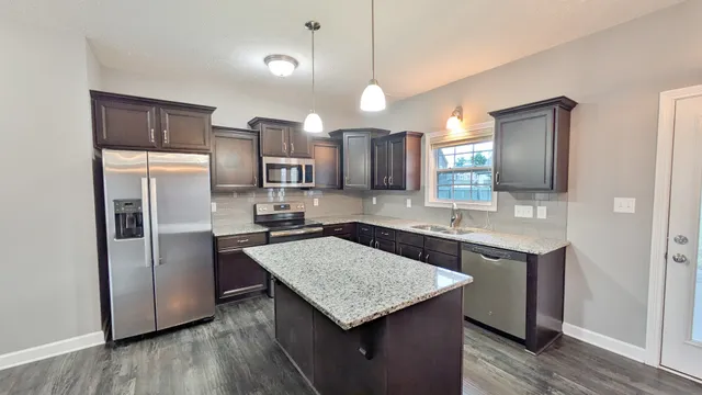a kitchen with kitchen island a counter top space a sink appliances and cabinets