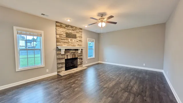 a view of an empty room with wooden floor fireplace and a window