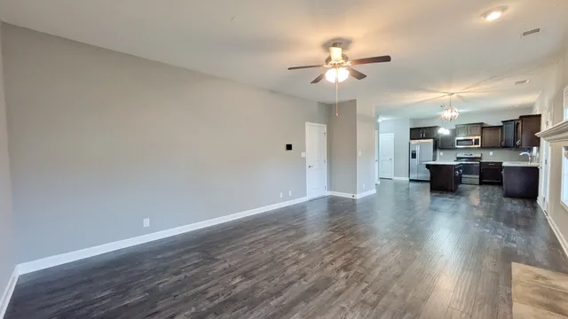 a view of a livingroom with furniture wooden floor a ceiling fan and kitchen