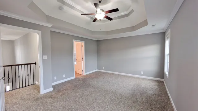 an empty room with chandelier fan and windows