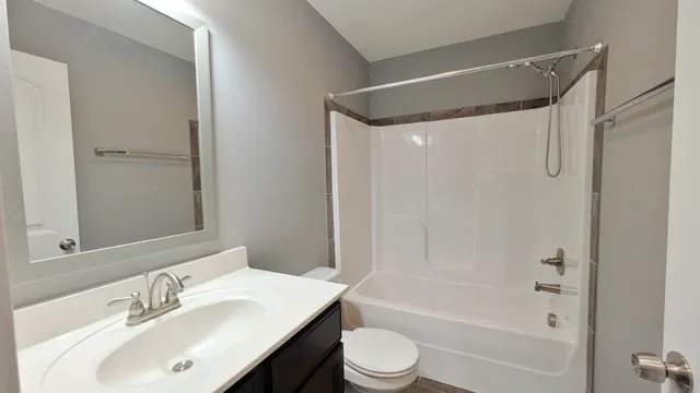 a bathroom with a bathtub shower sink vanity and toilet
