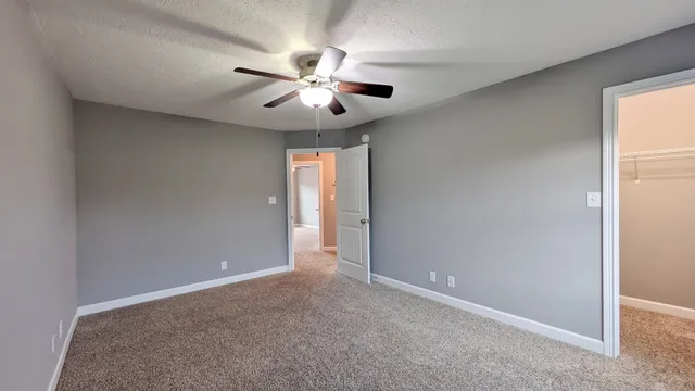 an empty room with windows and fan