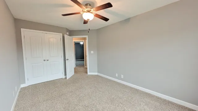 an empty room with closet and a chandelier fan