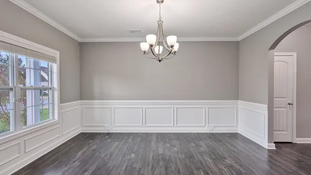 a view of an empty room with wooden floor and windows