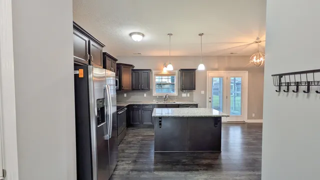 a kitchen with stainless steel appliances granite countertop a refrigerator a stove and a sink