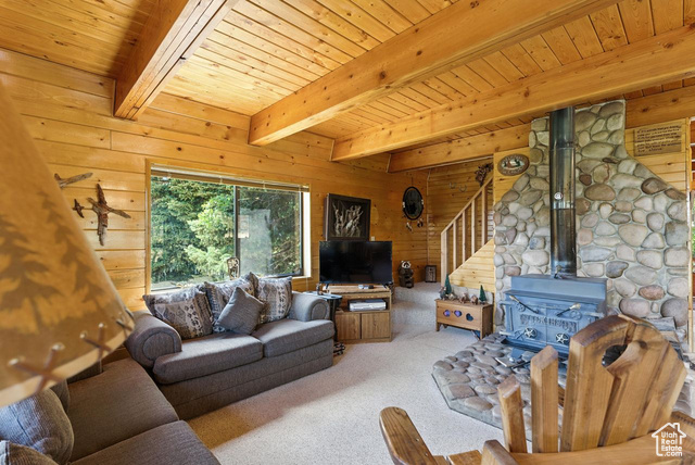 1180 Oak Road Coalville, UT 84017 - Photo 6 of 25 Living room with wood walls, a wood stove, a wood ceiling with exposed beams, carpet floors, and stairs