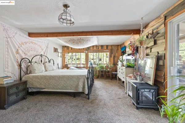 a spacious bedroom with a bed a mirror on dresser and a large window