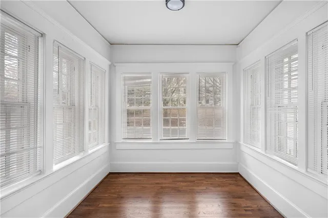 a view of an empty room with a window and wooden floor