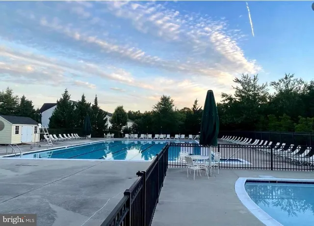 a view of swimming pool with seating space and trees in the background