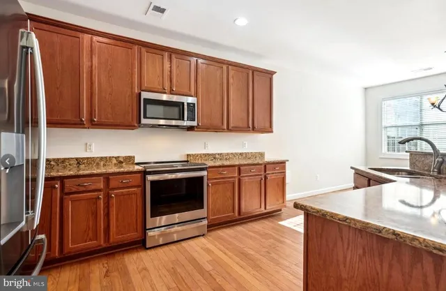 a kitchen with granite countertop wooden cabinets and stainless steel appliances