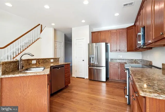 a kitchen with a refrigerator a stove top oven a sink and dishwasher with wooden floor