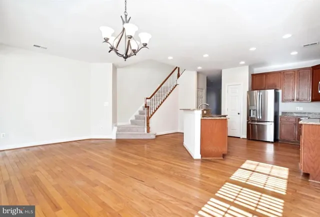 a view of a kitchen with stainless steel appliances wooden floor and a chandelier