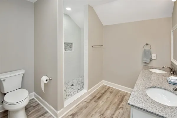a bathroom with a granite countertop sink a toilet and shower