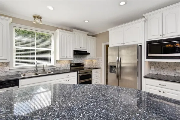 a kitchen with granite countertop a refrigerator and a stove top oven