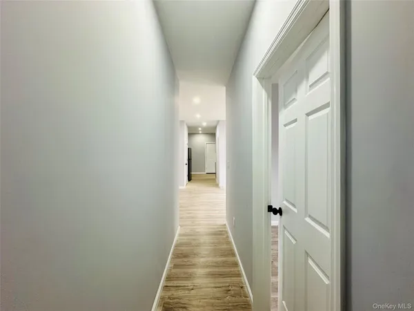 a view of a hallway with wooden floor and a bathroom