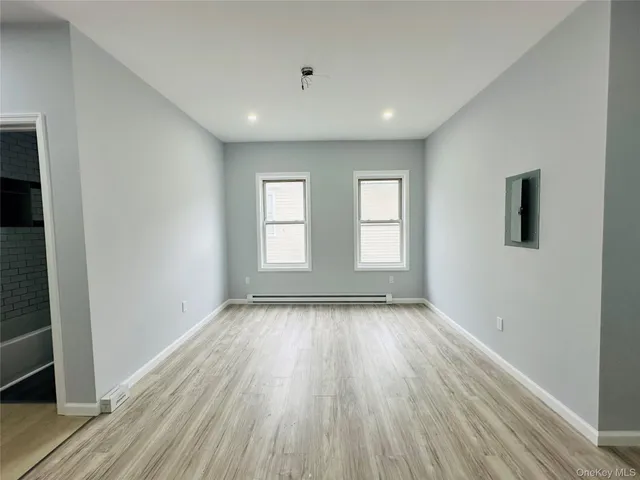 a view of an empty room with wooden floor and window