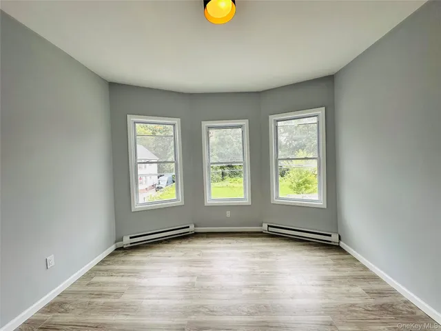 a view of an empty room with window and wooden floor