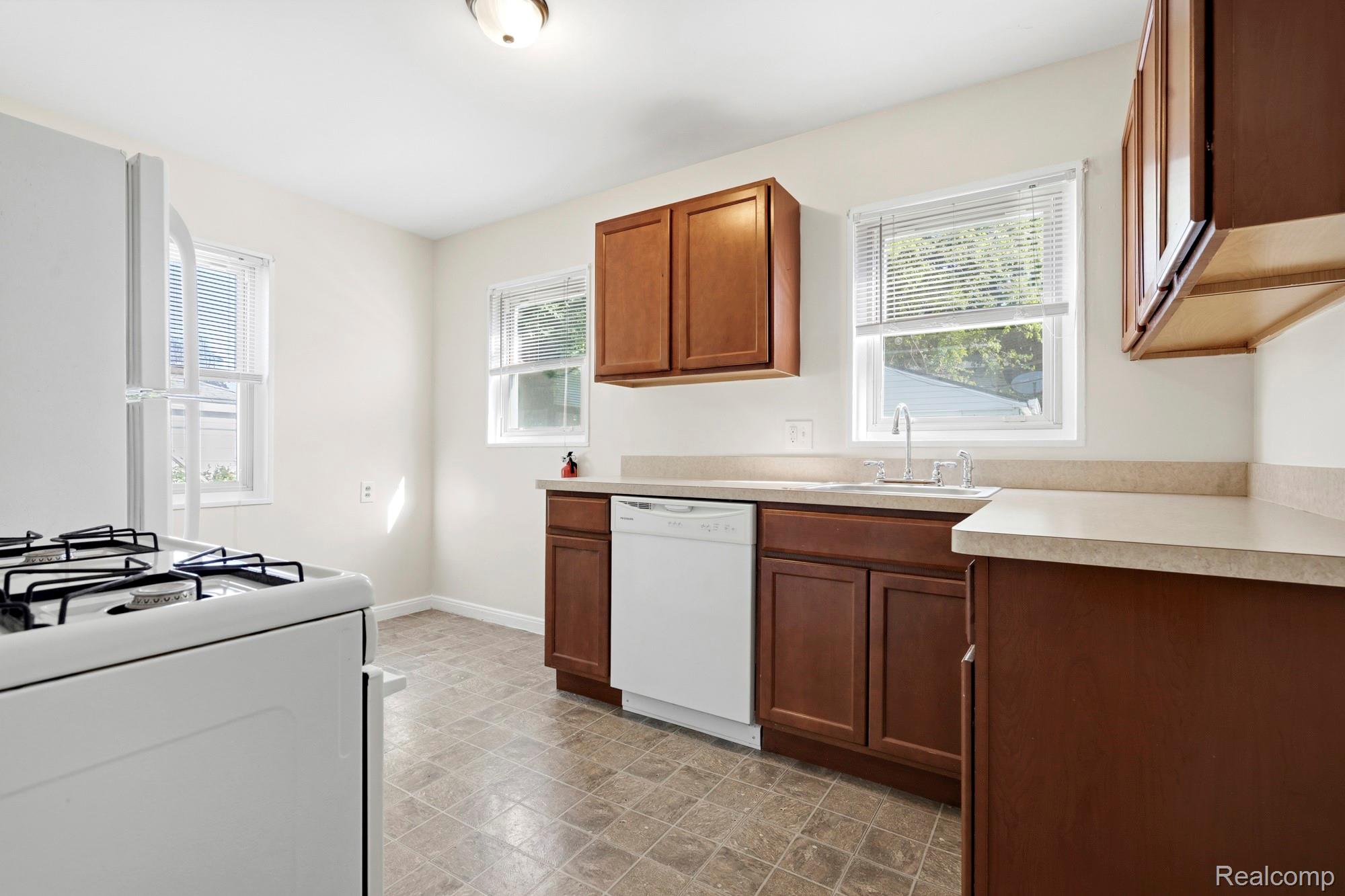 970 Champaign Road Lincoln Park, MI 48146 - Photo 15 of 28 Kitchen with light countertops, white appliances, plenty of natural light, and wood finish cabinets