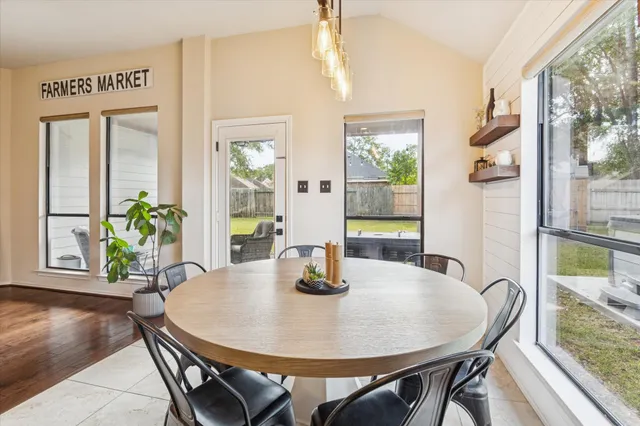 a dining room with wooden floor a chandelier a wooden table and chairs