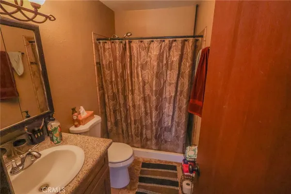 a bathroom with a granite countertop sink toilet and mirror