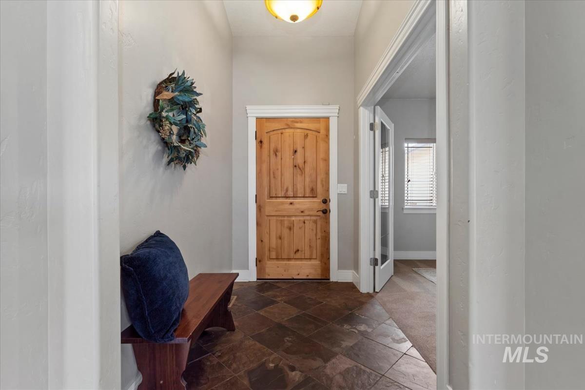 640 Southwest Miner Street Mountain Home, ID 83647 - Photo 4 of 35 Entryway featuring slate tile flooring, a natural wood door with white trim, and an overhead light fixture
