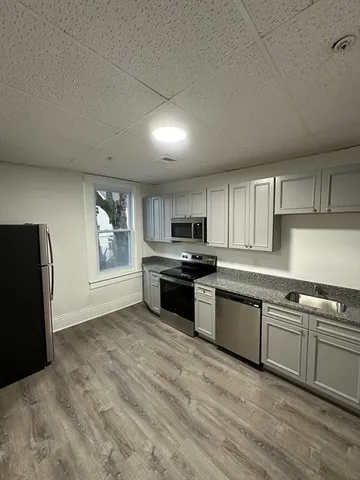 a kitchen with granite countertop a stove top oven sink and cabinets