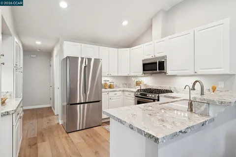 a kitchen with granite countertop a refrigerator a sink a stove a microwave and wooden floor