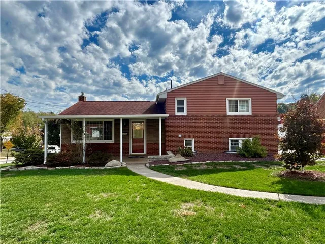 a front view of a house with a garden and trees