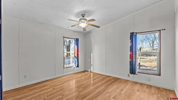 a view of an empty room with window and wooden floor