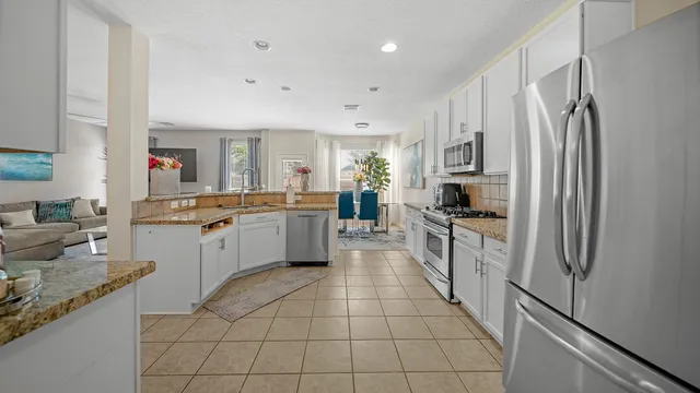 a large kitchen with a stove a sink dishwasher a refrigerator and a oven with wooden floor