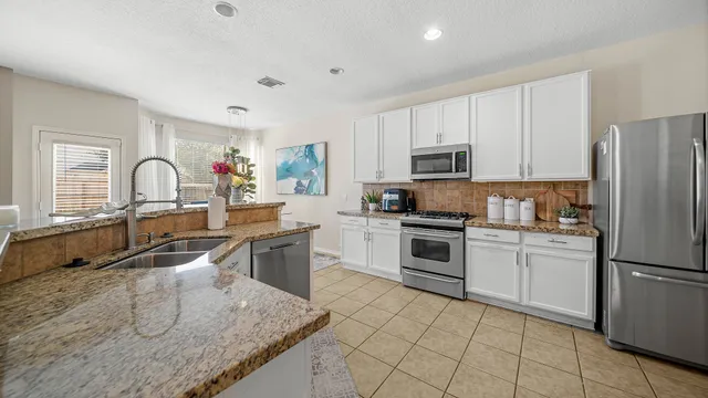 a kitchen with granite countertop a stove sink and refrigerator