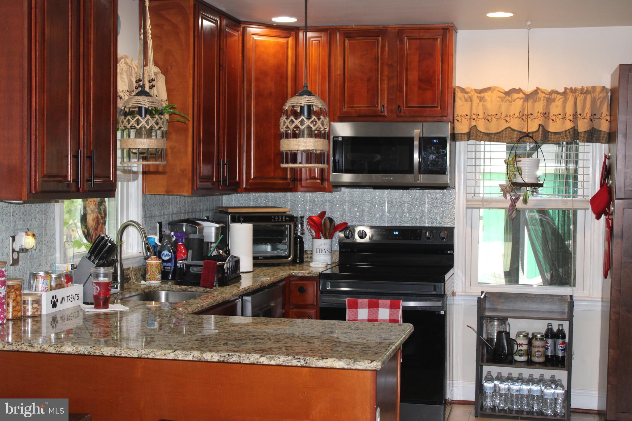 7802 Shelbourne Road Baltimore, MD 21226 - Photo 2 of 19 a kitchen with granite countertop a stove a sink and a microwave