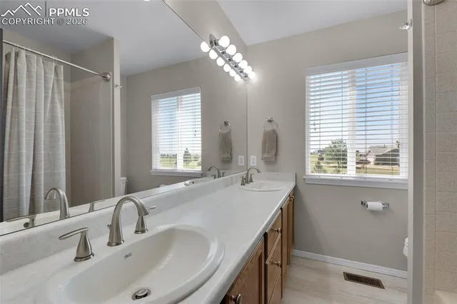 a bathroom with double vanity and a mirror