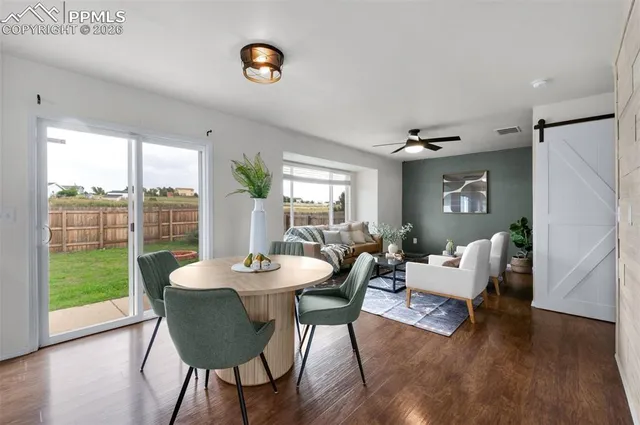 a dining room with wooden floor a chandelier a glass table and chairs