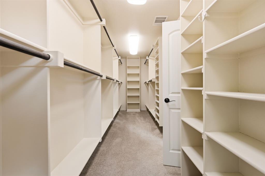 7013 Handel Colleyville, TX 76034 - Photo 22 of 37 Spacious walk-in closet featuring extensive built-in shelving, multiple hanging rods, light-colored carpeting, and recessed lighting