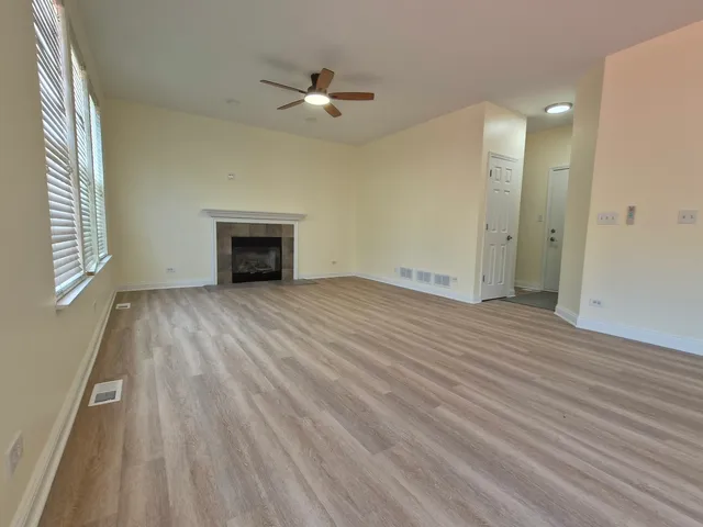 an empty room with wooden floor fireplace and windows