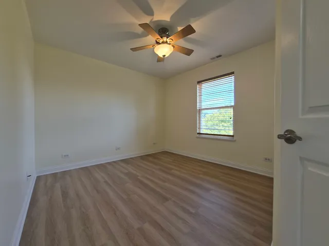 an empty room with a window and a ceiling fan