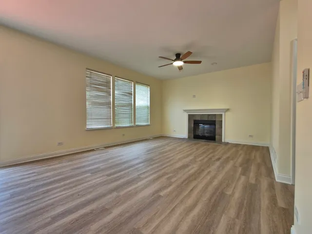 an empty room with wooden floor fireplace and windows