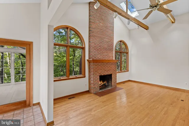 an empty room with windows fireplace and wooden floor
