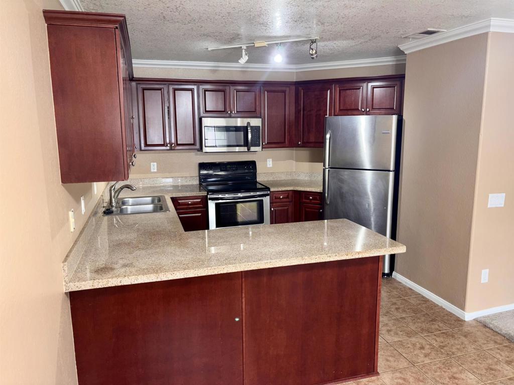 3545 Paseo De Francisco, Unit 225 Oceanside, CA 92056 - Photo 8 of 34 a kitchen with stainless steel appliances a refrigerator a sink a stove a microwave and island