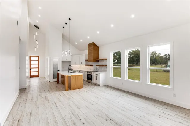 a view of an empty room with a window and a kitchen